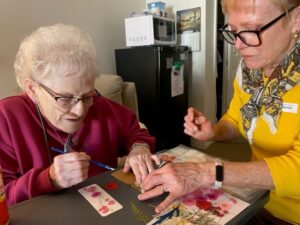 Ginny M. (L) and daughter-in-law Ann W., concentrating as they create a unique pressed flower bookmark. 